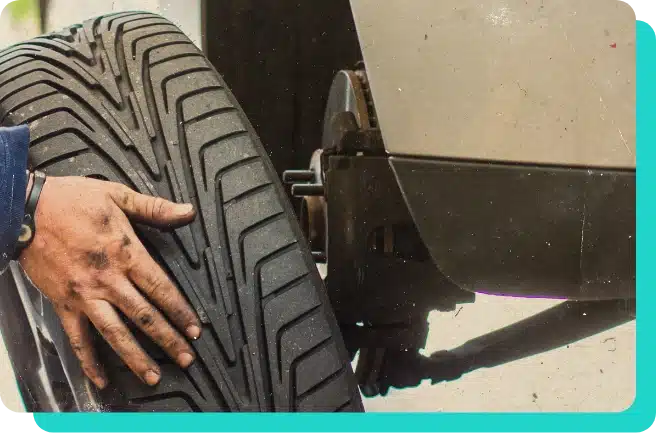 mechanic hand removing tire off of white truck on lift in the shop