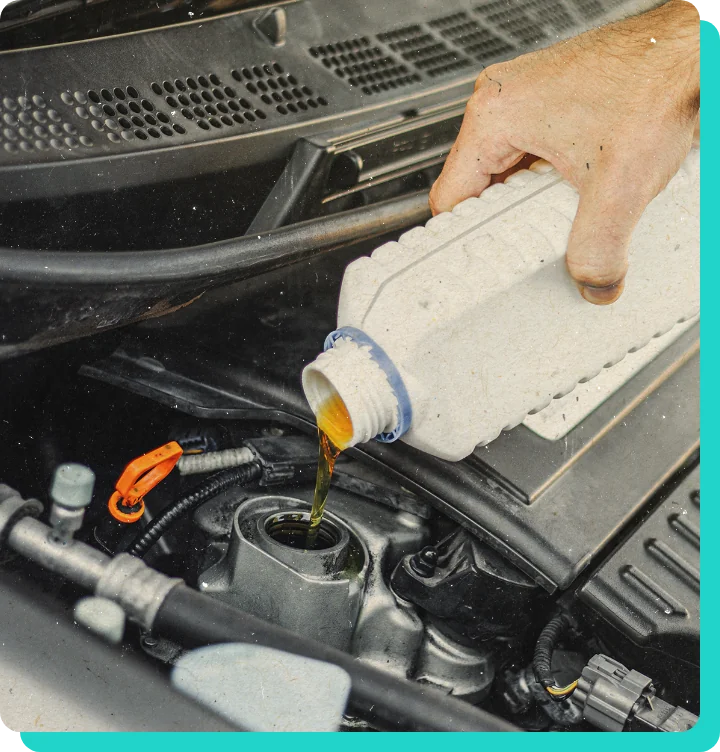 Mechanic hand pouring oil into car engine after an oil change in Wells, VT.