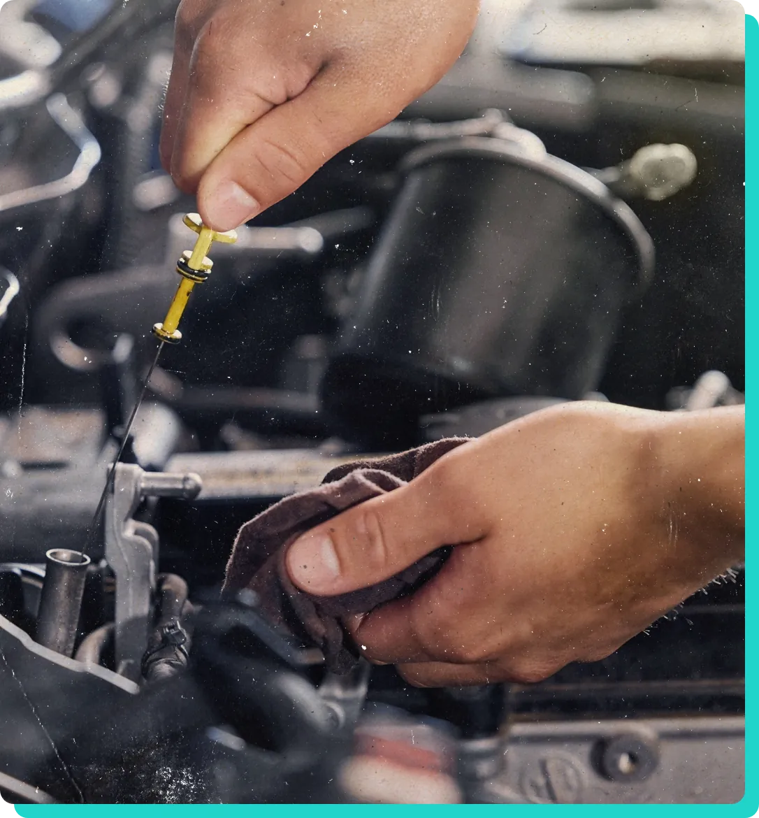 Oil change service in Wells, VT with Thomas' Auto Repair. Image o mechanic hand pulling on engine oil dipstick while holding a rag in the other hand to clean it to be able to check the oil in the engine.