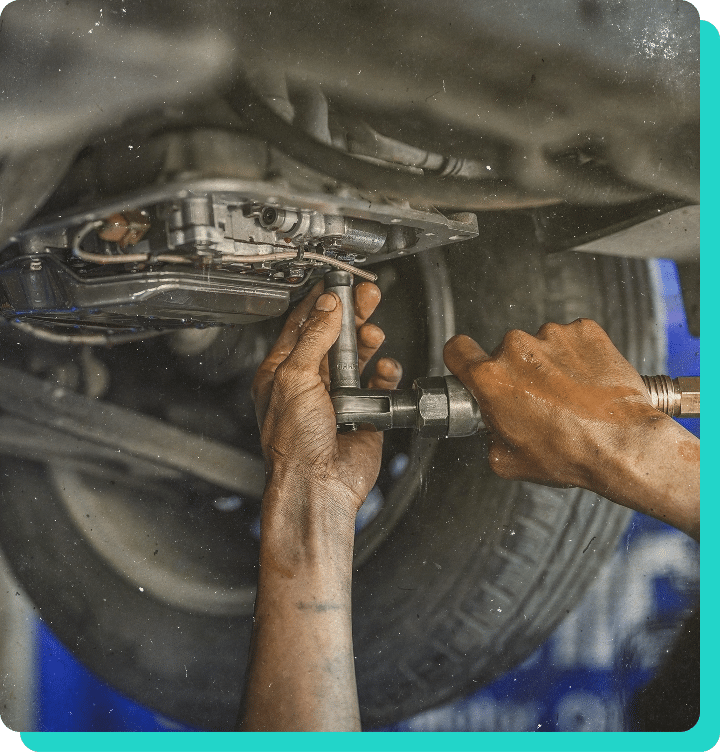 Image of mechanic hands turning tool to take transmission case cover off on a car in the shop for transmission fluid exchange in Wells, VT.