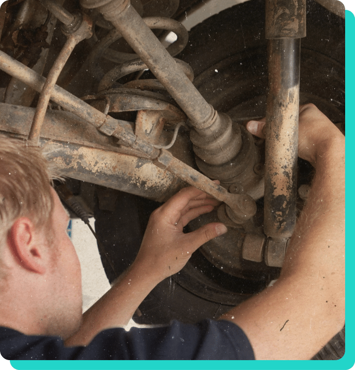 Mechanic handling the suspension components on a vehicle in the shop while coming in for a Vermont State Inspection.