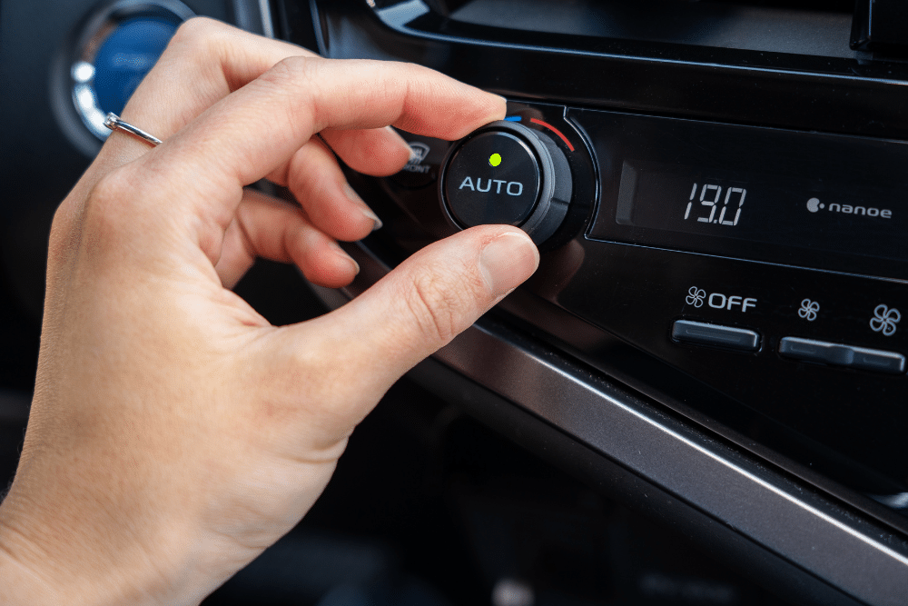 Auto Air Conditioning Repair in Wells, VT at Thomas' Auto Repair. Image of Driver adjusting vehicle AC climate control dial in Wells, VT.
